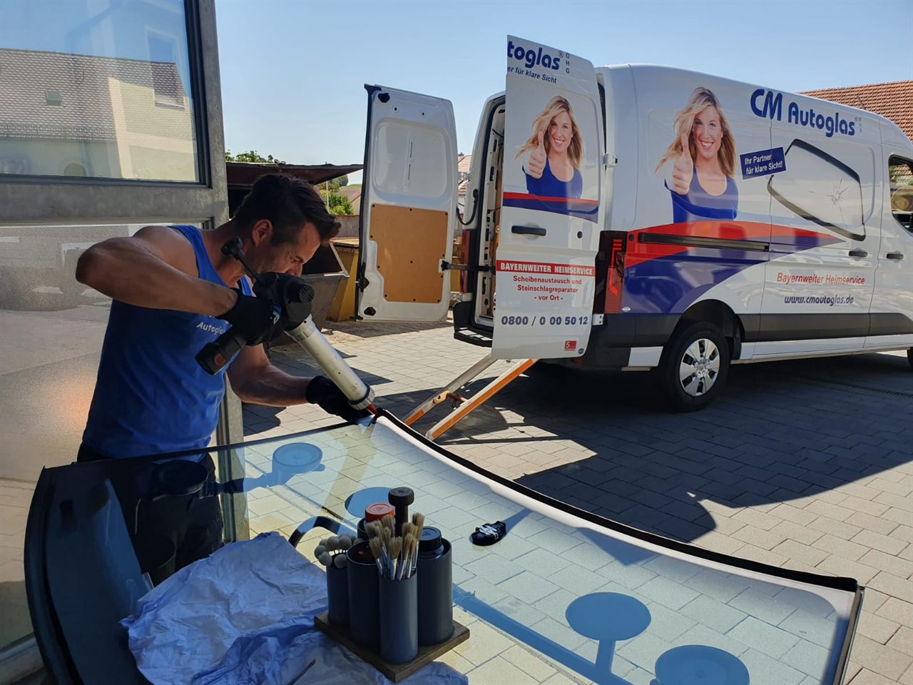 Mobiler Einsatz: Monteur arbeitet neben dem Servicefahrzeug von CM Autoglas an einer neuen Scheibe