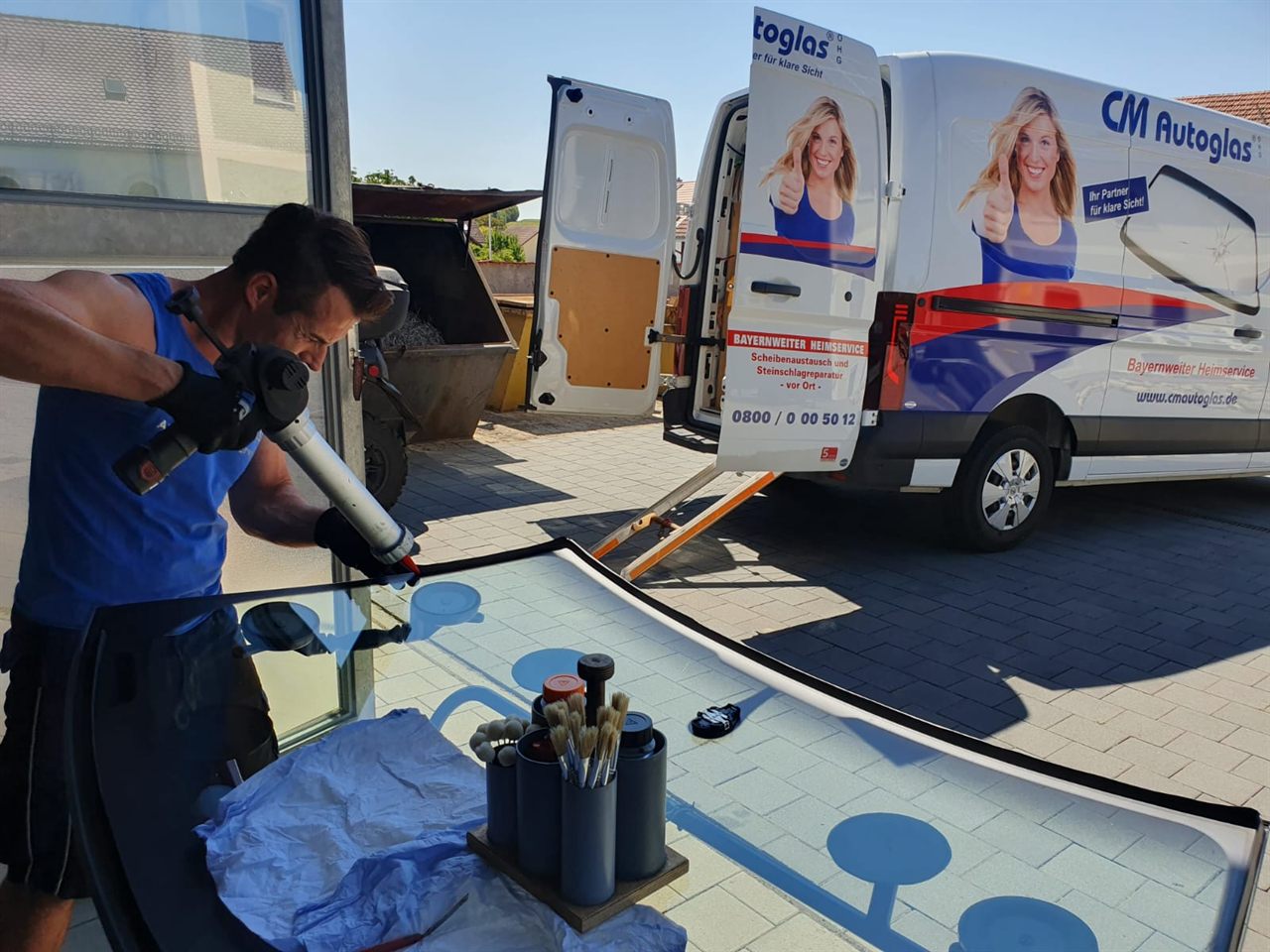 Monteur bereitet vor dem Servicefahrzeug eine neue Windschutzscheibe für den Einbau vor